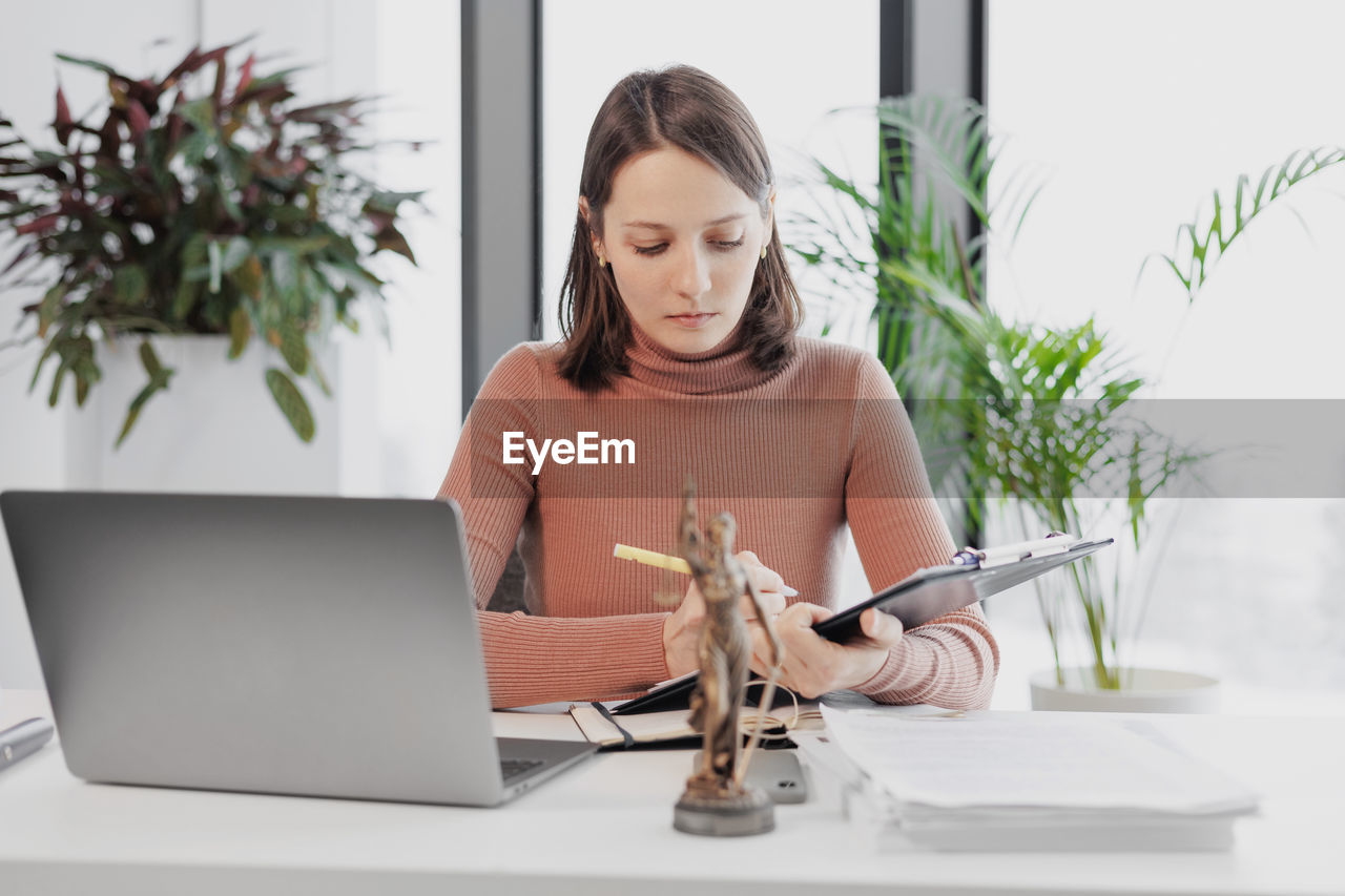 young woman using laptop while sitting at table