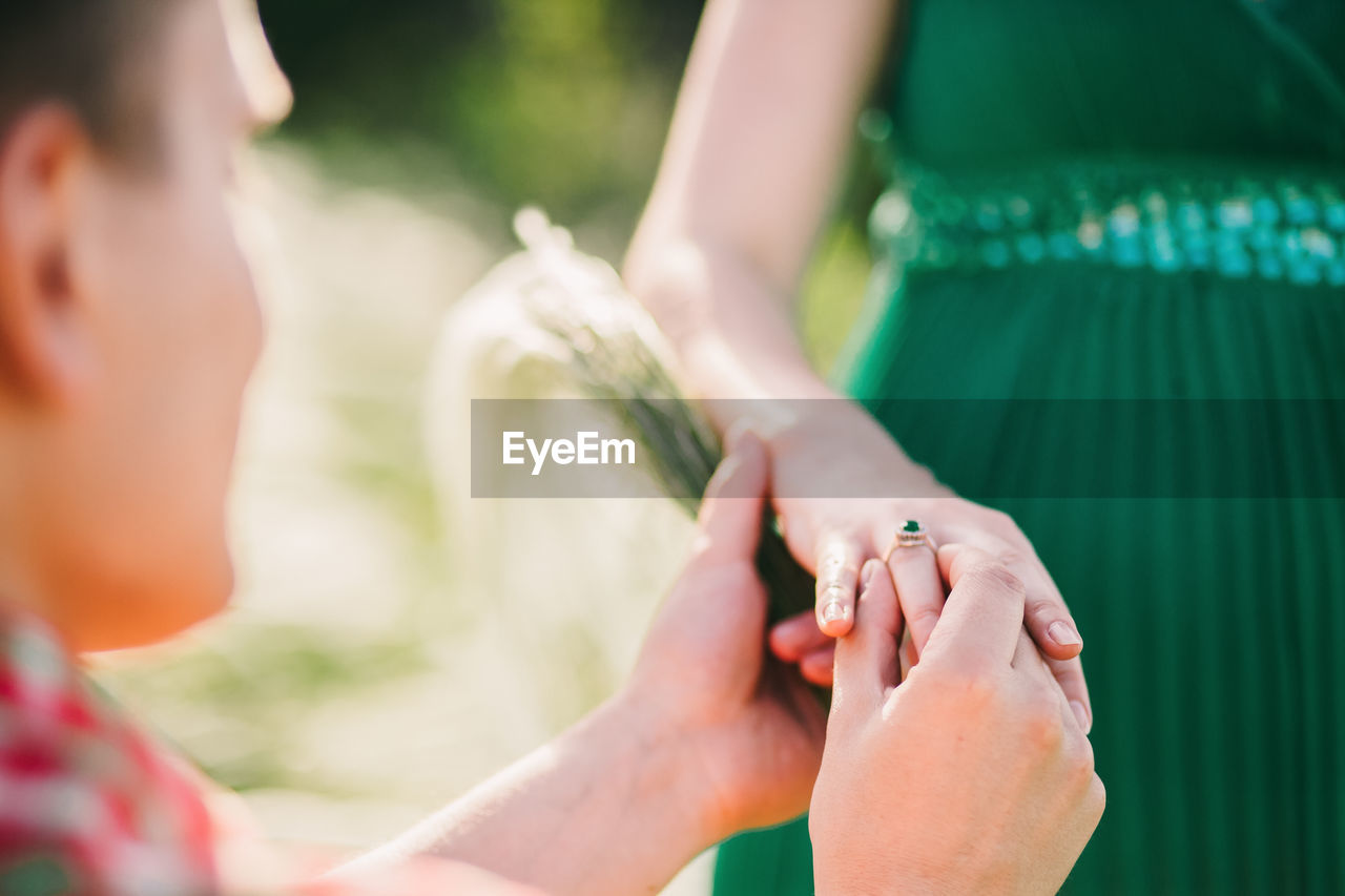 MIDSECTION OF COUPLE HOLDING HANDS ON TREE