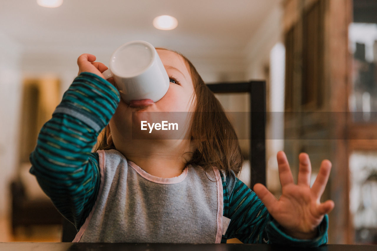 Close-up portrait of girl having drink at home