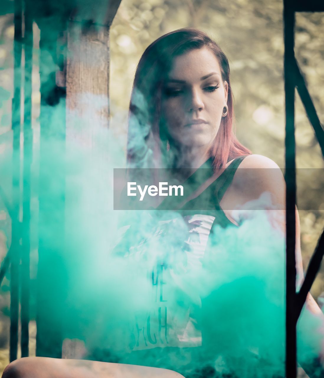 Young woman with smoke standing at park