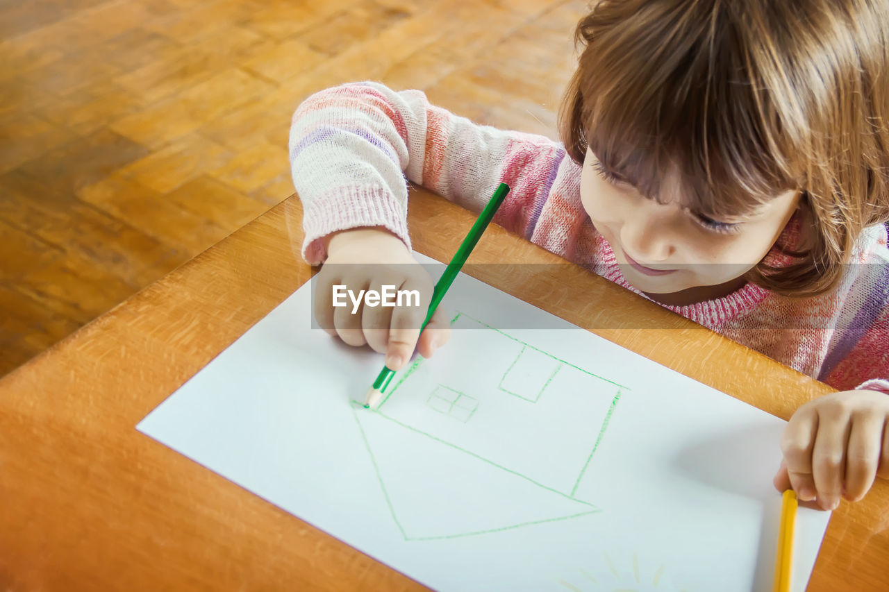 high angle view of girl drawing on book