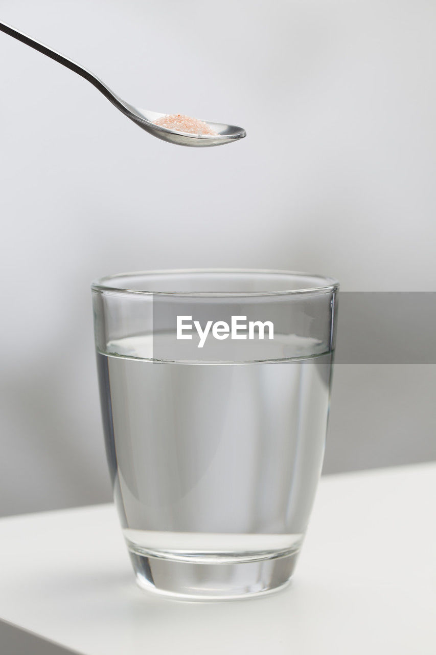 cup, spoon, household equipment, tableware, food and drink, kitchen utensil, glass, drinking glass, studio shot, indoors, water, drink, refreshment, white background, food, no people, eating utensil, drinking water, wellbeing, transparent, close-up, freshness, simplicity