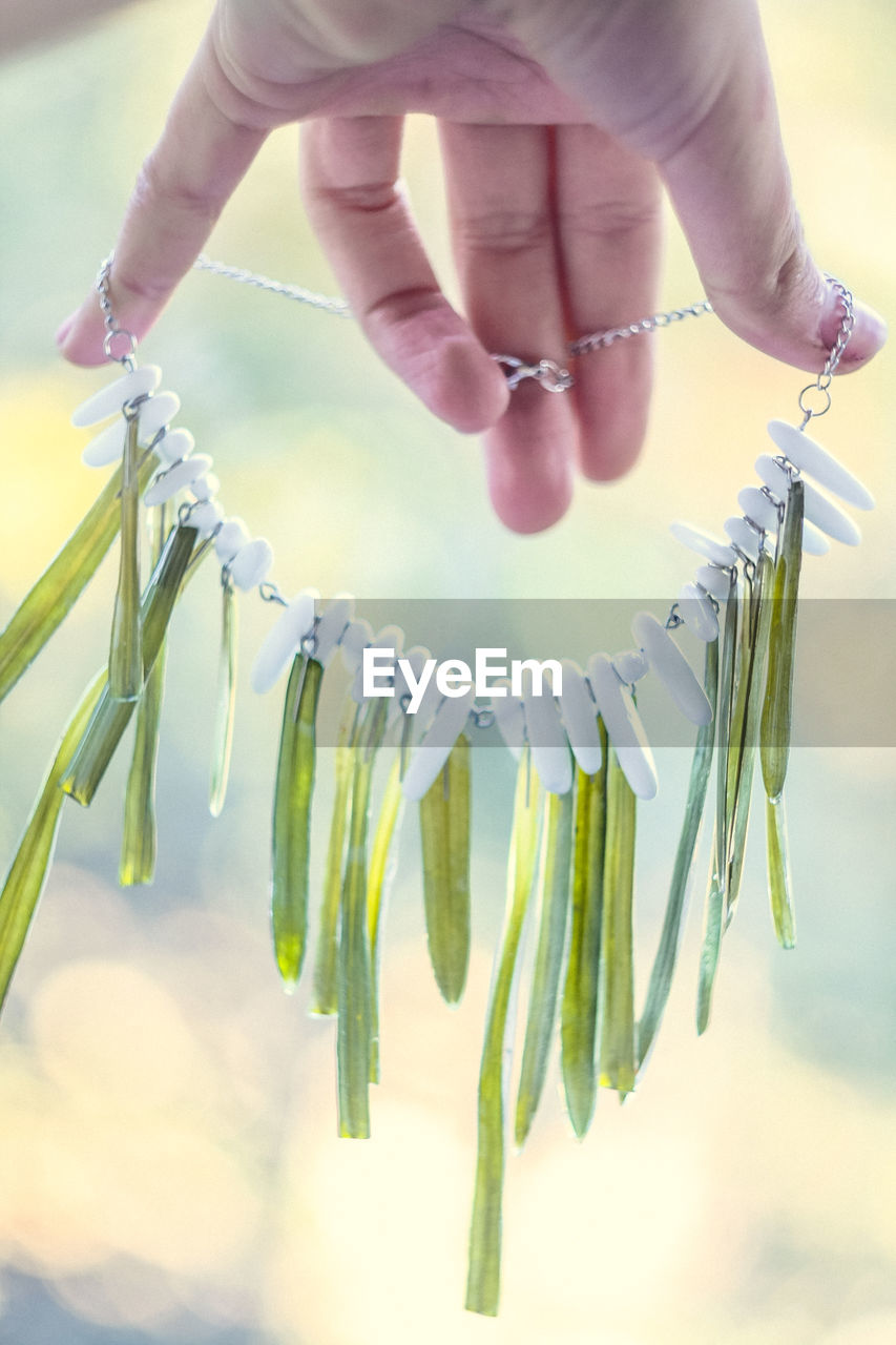 Close up lady holding necklace with grass and white gems concept photo