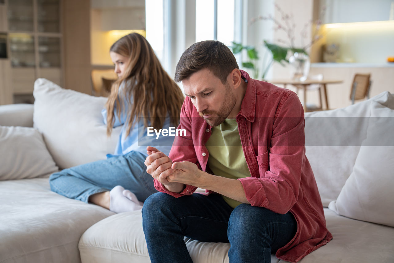 side view of young woman using laptop while sitting on sofa at home