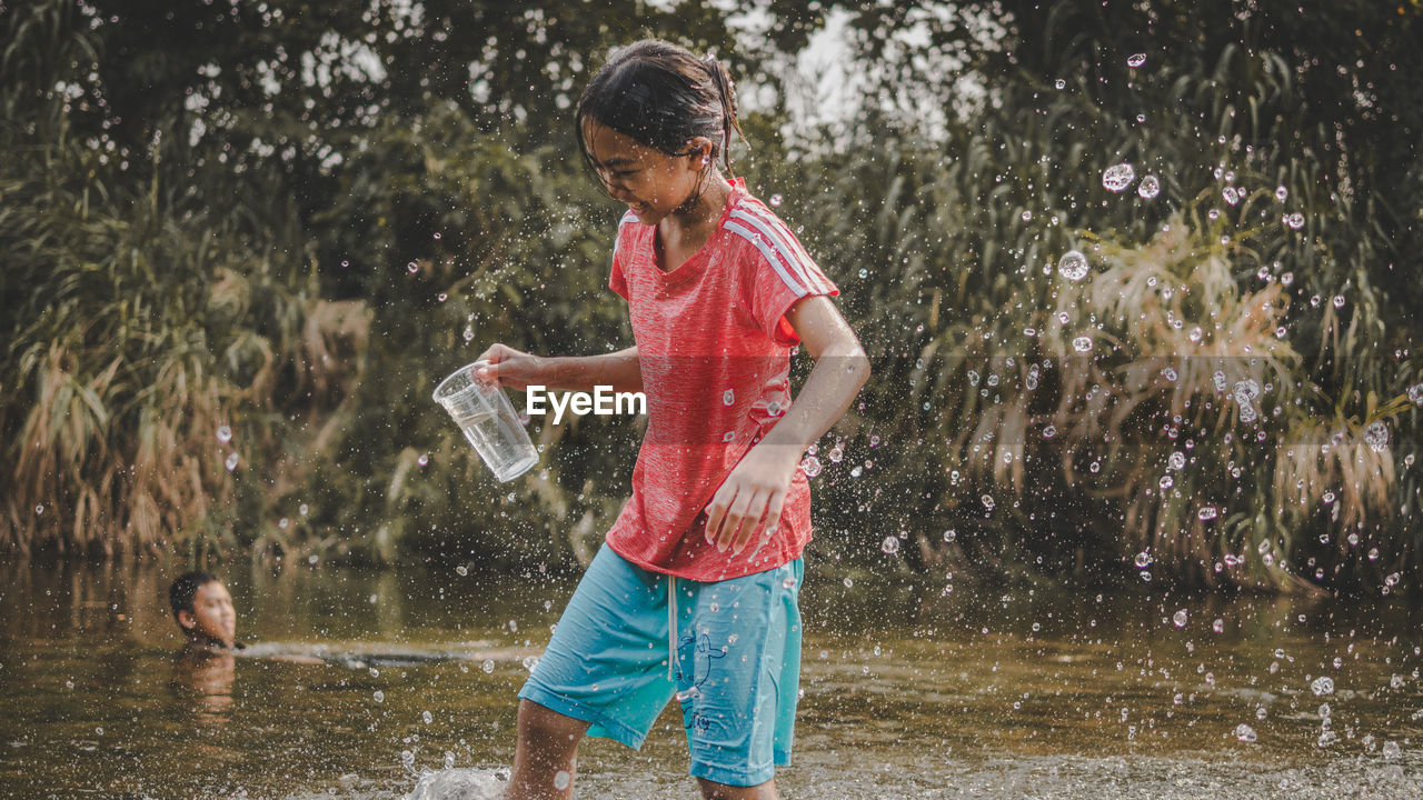 FULL LENGTH OF MAN PLAYING WITH WATER IN PARK