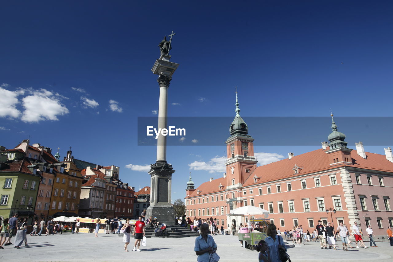 People at sigismund column by royal castle against sky