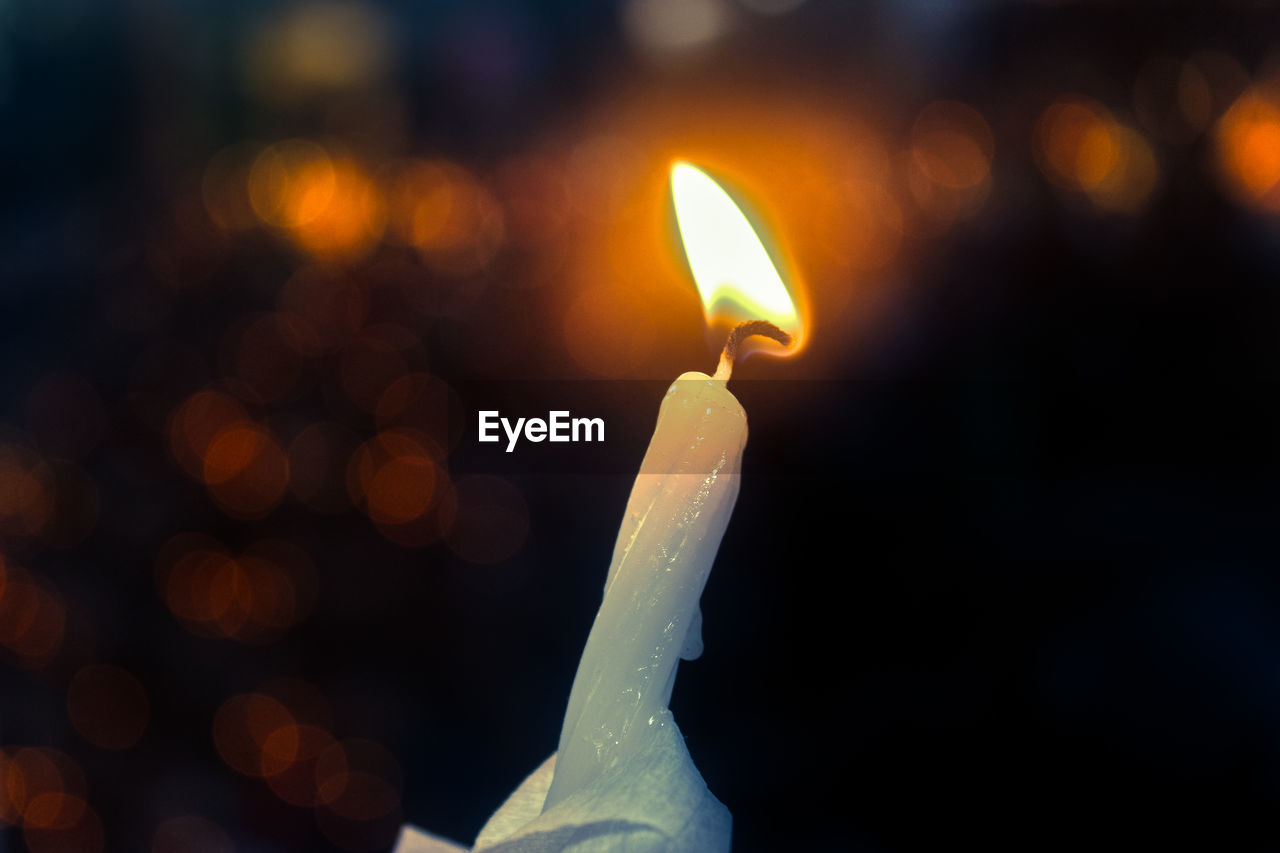 CLOSE-UP OF LIT CANDLES IN THE DARK