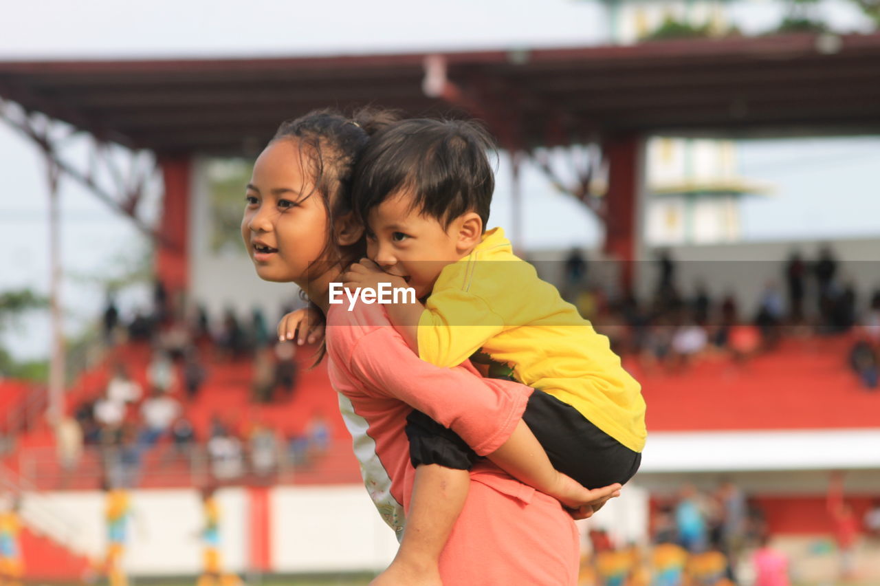 The older sister holds her younger sibling with affection