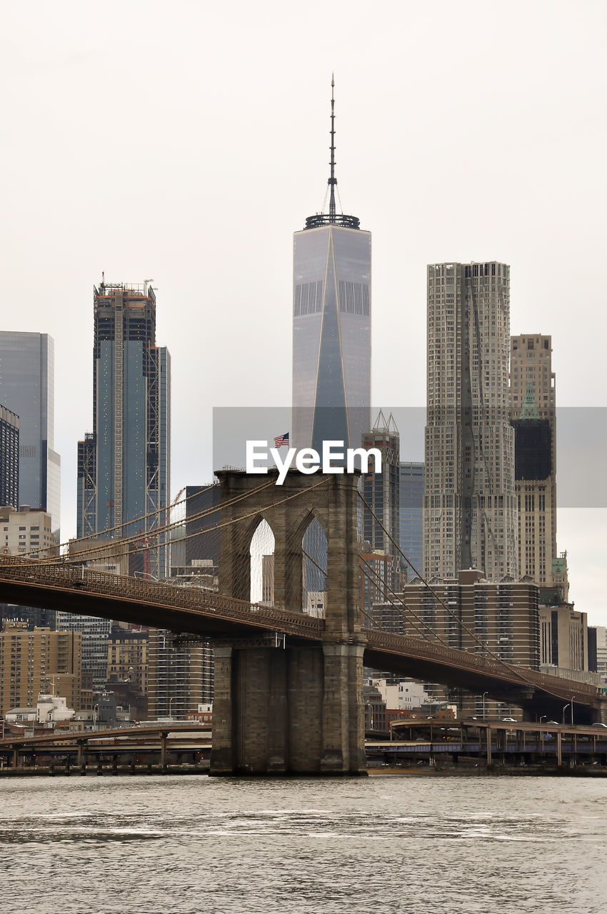 Modern buildings by river against clear sky