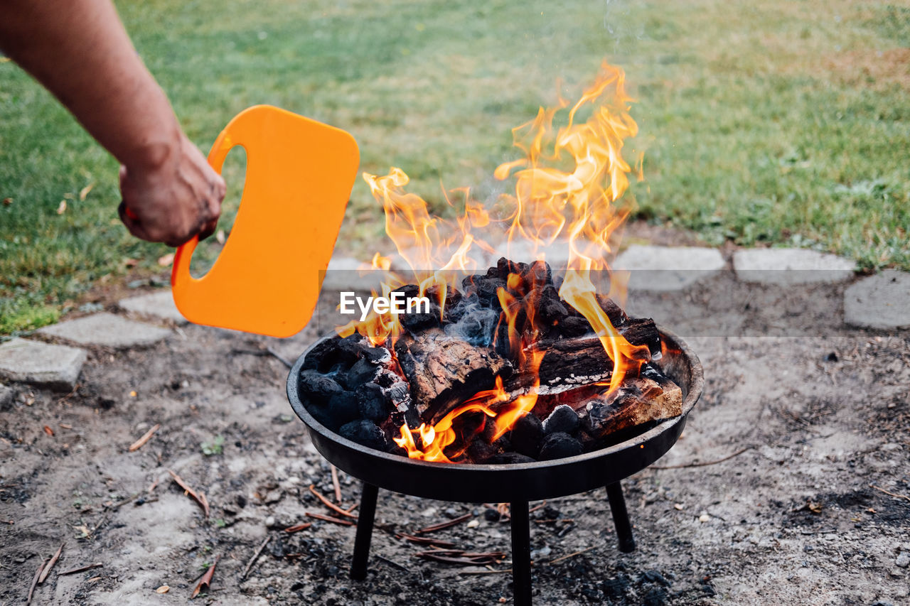 How to use a charcoal grill. man with plastic bbq hand fan near charcoal grill fire. barbeque