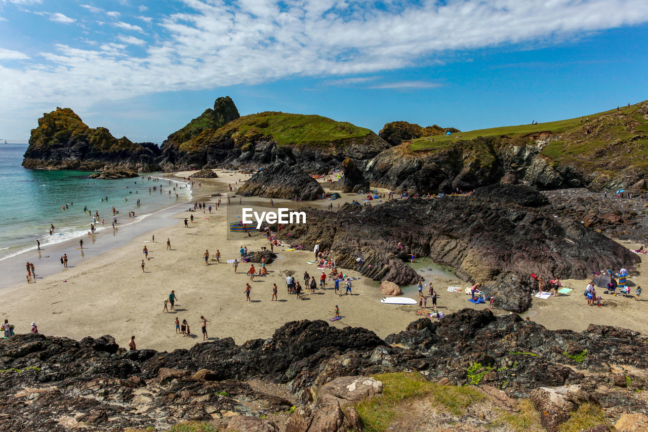 GROUP OF PEOPLE ON BEACH AGAINST MOUNTAIN