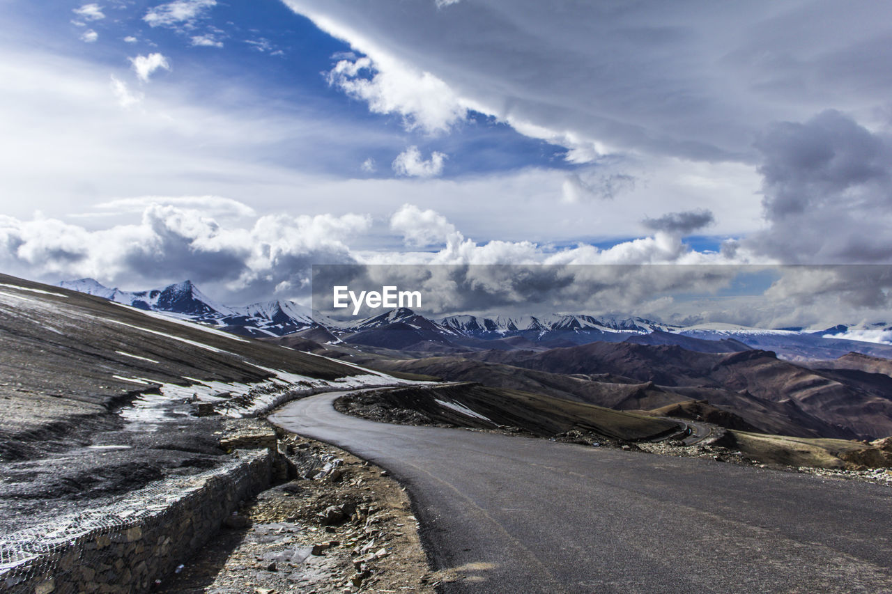 ROAD BY SNOWCAPPED MOUNTAINS AGAINST SKY