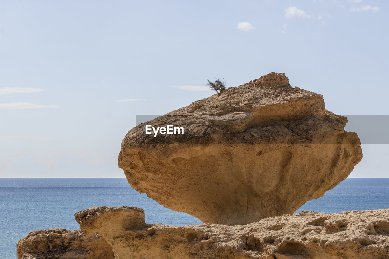 Rock formation on beach against sky