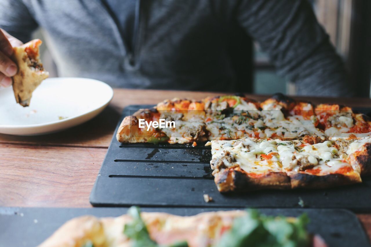 Midsection of man having pizza in restaurant