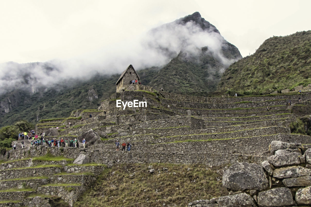 PANORAMIC VIEW OF PEOPLE ON LANDSCAPE AGAINST MOUNTAIN