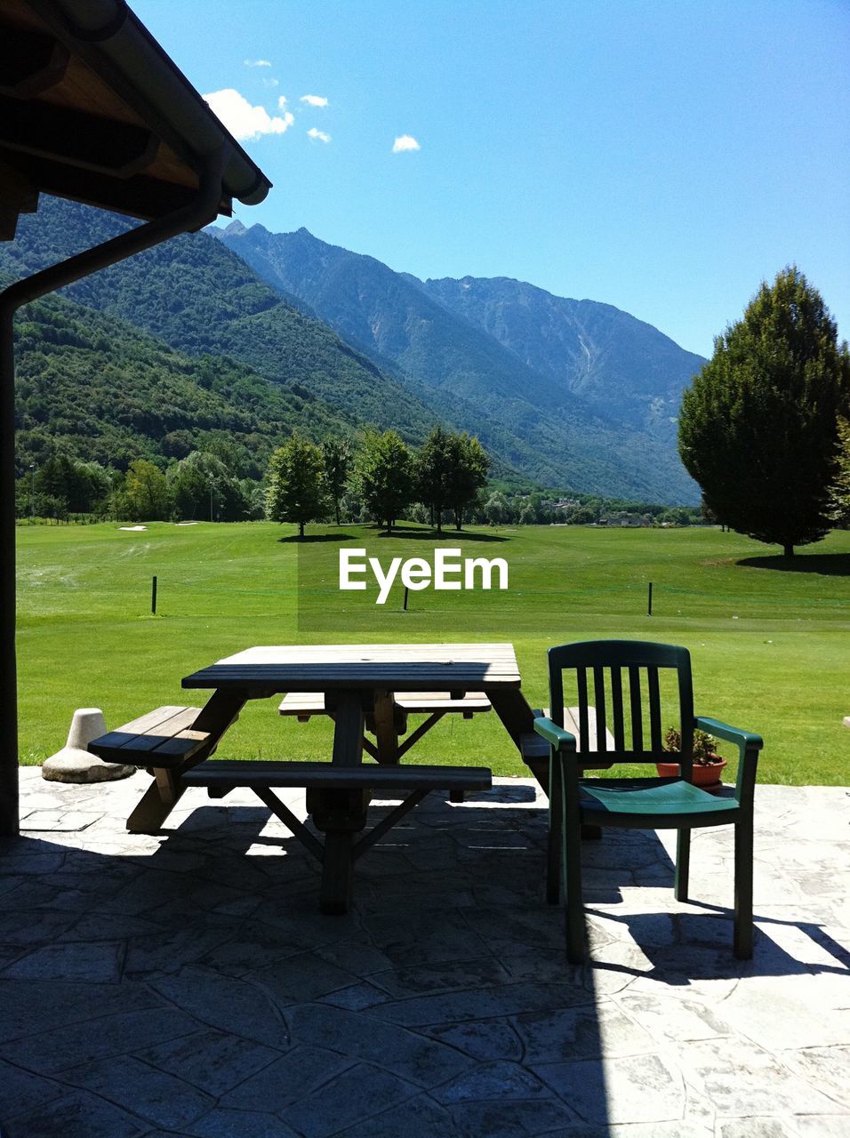 EMPTY CHAIRS AND TABLE AGAINST TREES ON MOUNTAIN