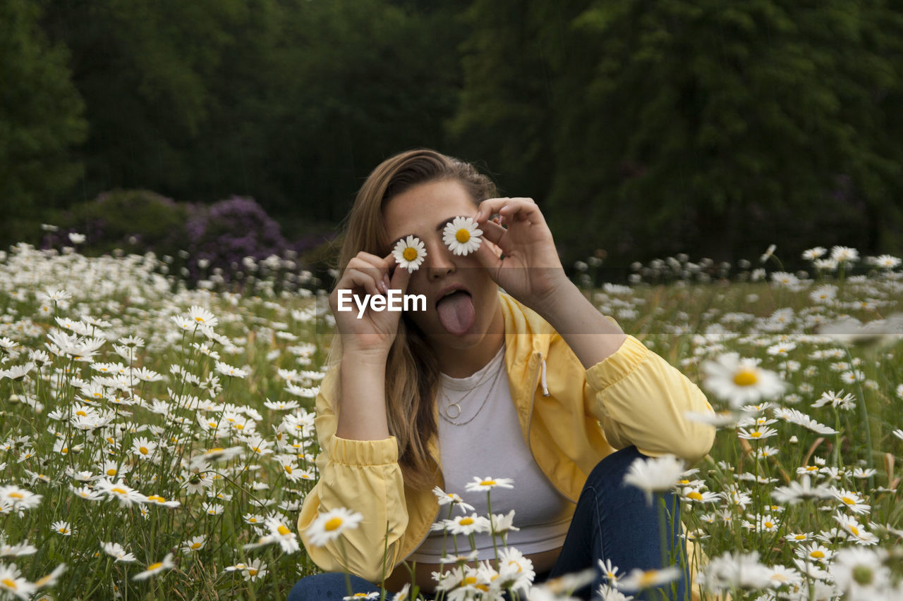 Woman holding flowers on eyes