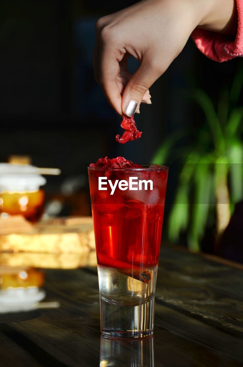 close-up of hand holding drink in glass on table