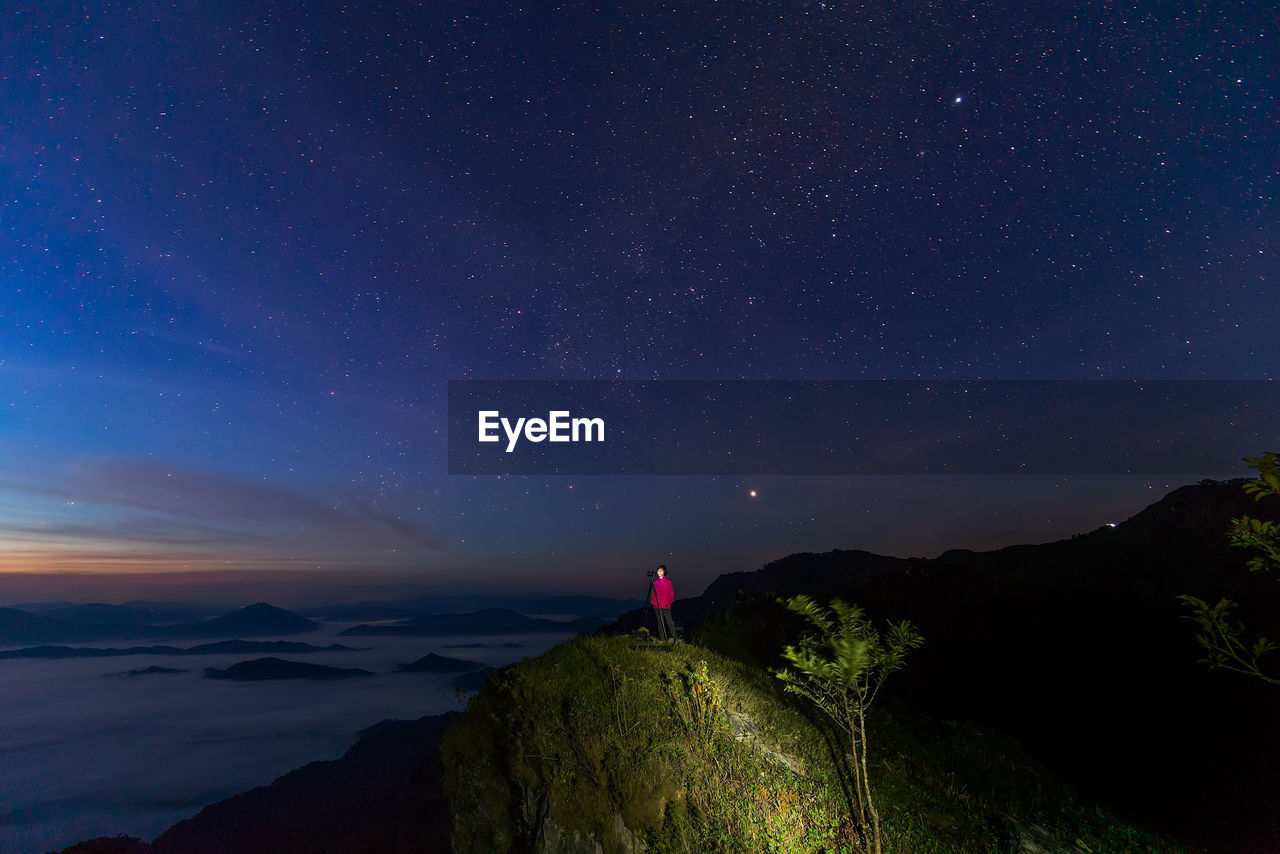 Woman on mountain against sky at night