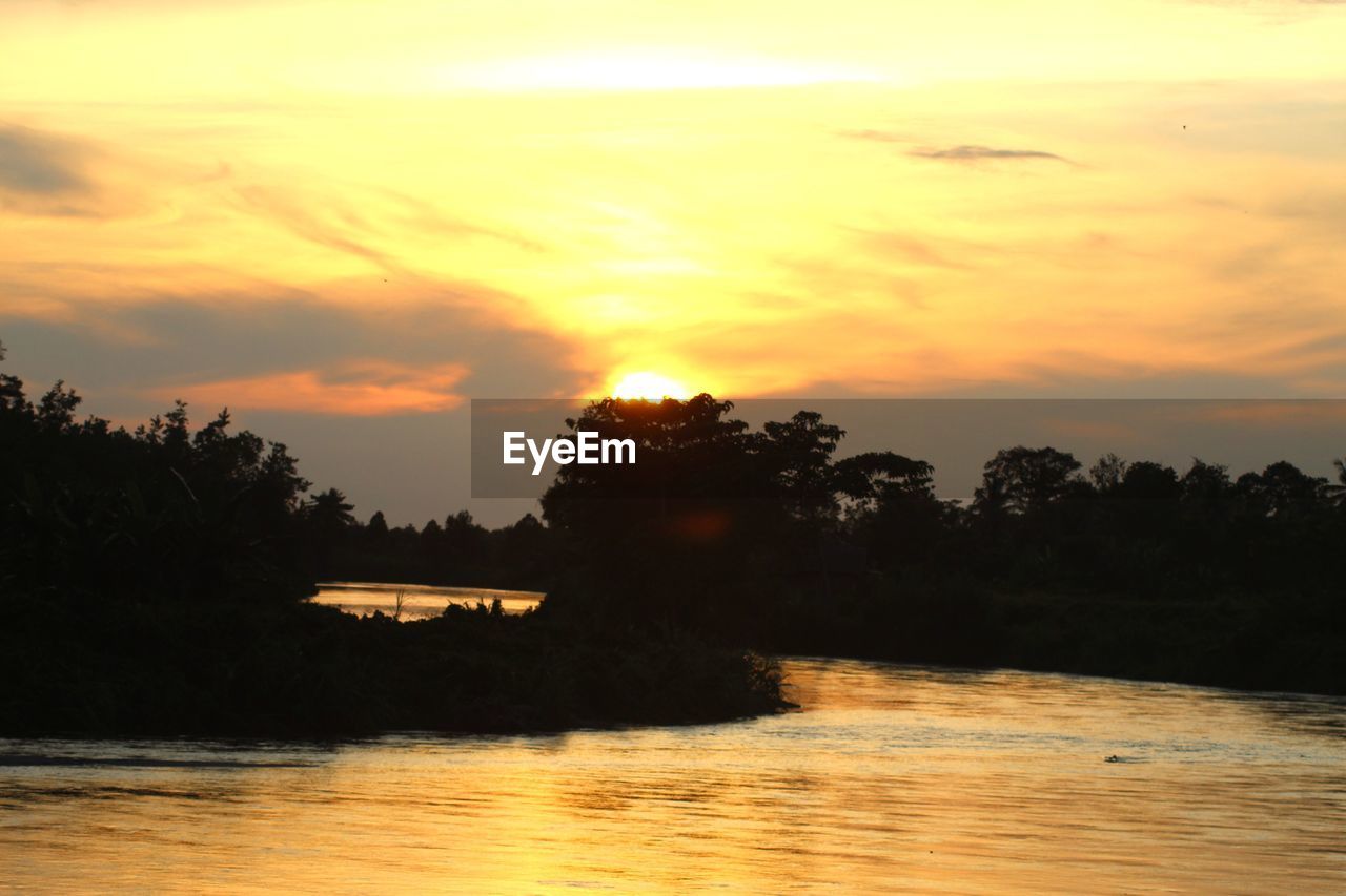 SILHOUETTE TREES BY LAKE AGAINST ORANGE SKY