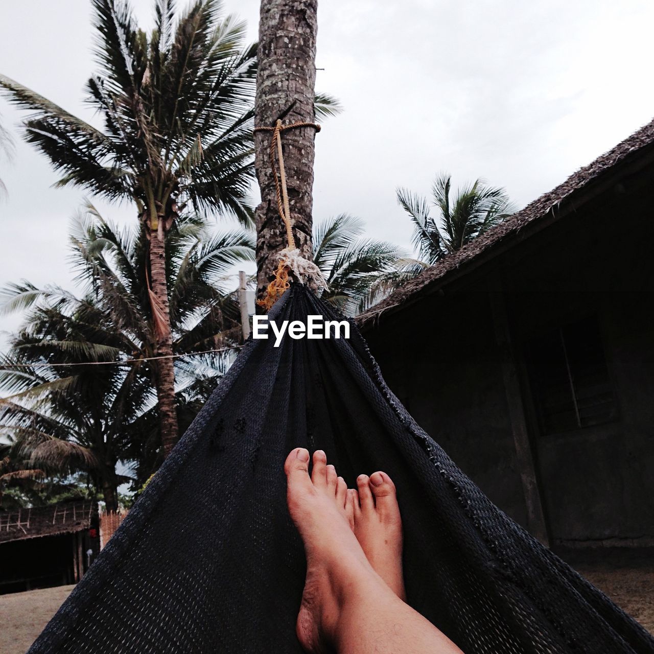 Low section of man on hammock against sky