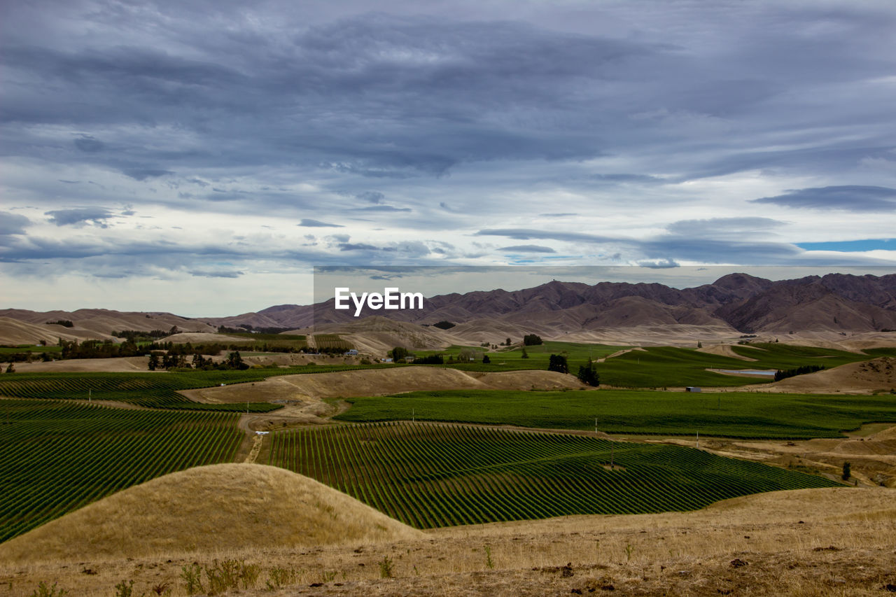 High angle view of crop field against mountains and cloudy sky