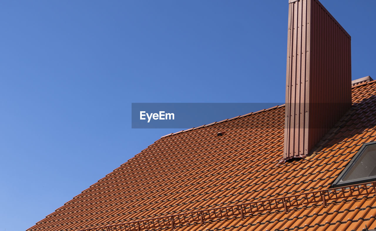 LOW ANGLE VIEW OF BUILDING ROOF AGAINST BLUE SKY