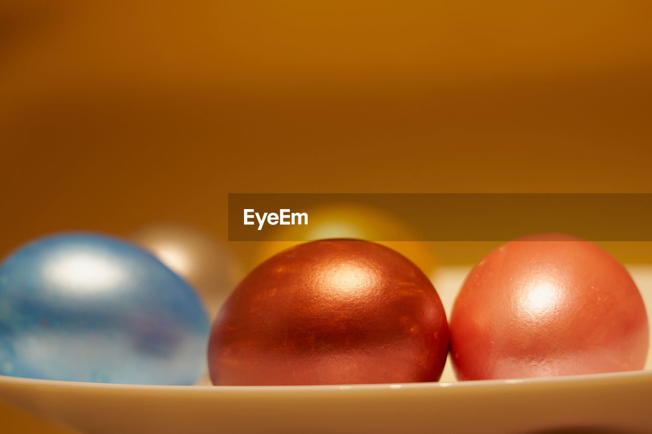 Painted eggs on a white plate with golden background.