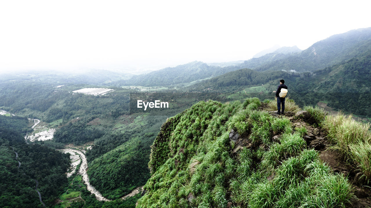 REAR VIEW OF MAN LOOKING AT MOUNTAINS