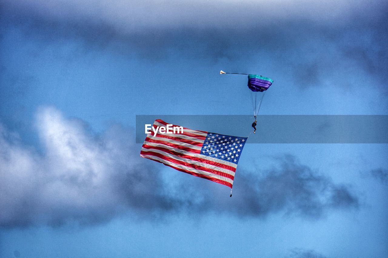Person paragliding with american flag in sky
