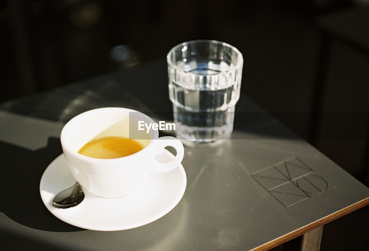 CLOSE-UP OF COFFEE CUP AND GLASS ON TABLE