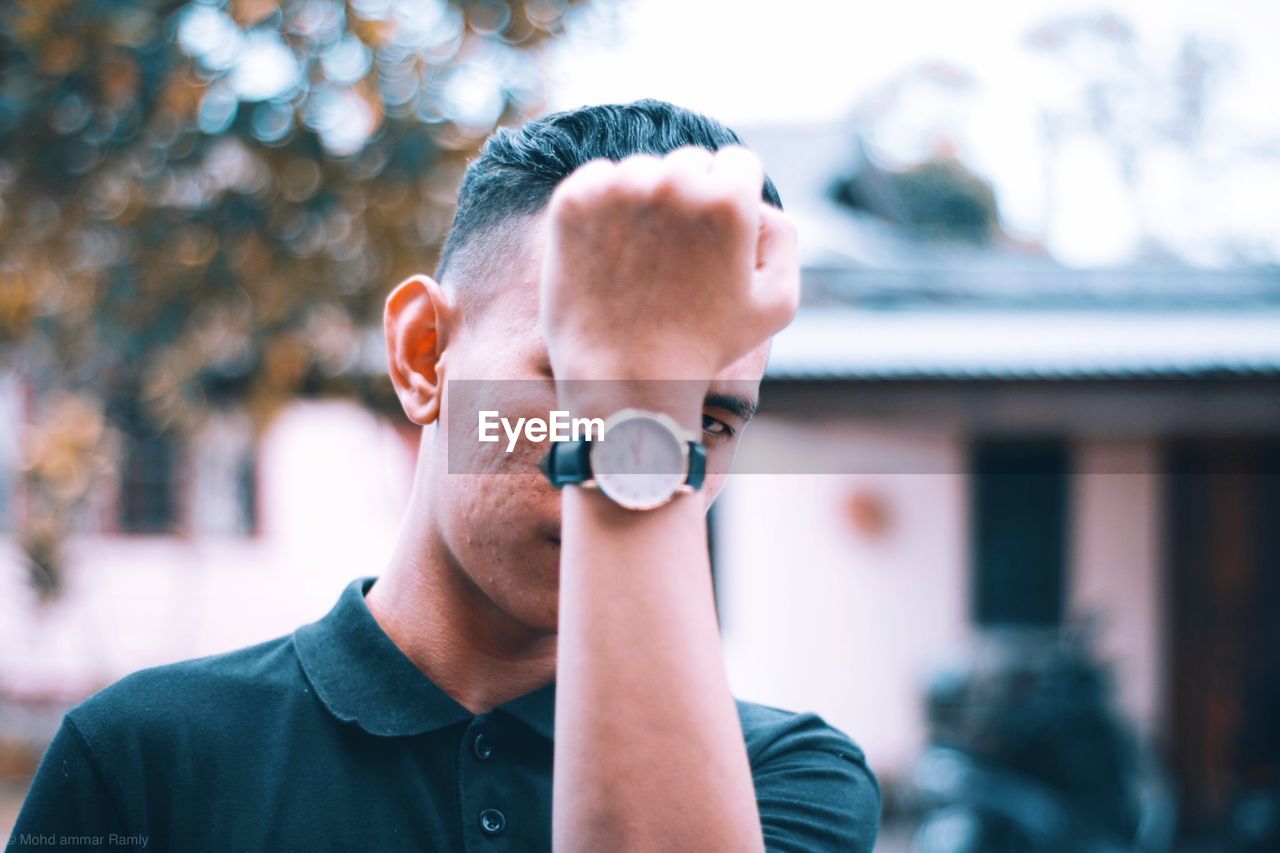 PORTRAIT OF MAN HOLDING CAMERA OUTDOORS