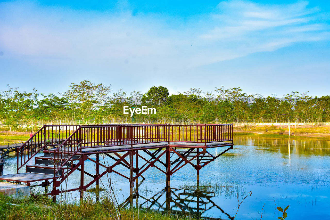 Reflection of trees in swimming pool against sky