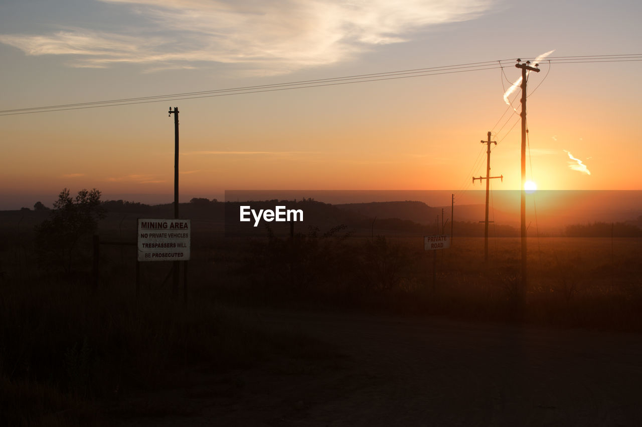 SILHOUETTE OF ELECTRICITY PYLON AGAINST SUNSET SKY