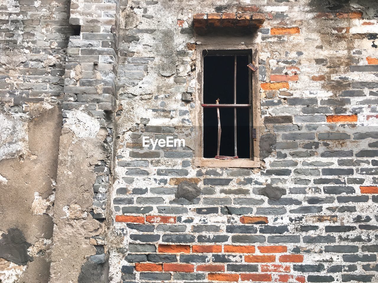 LOW ANGLE VIEW OF WINDOW ON BRICK WALL OF OLD BUILDING