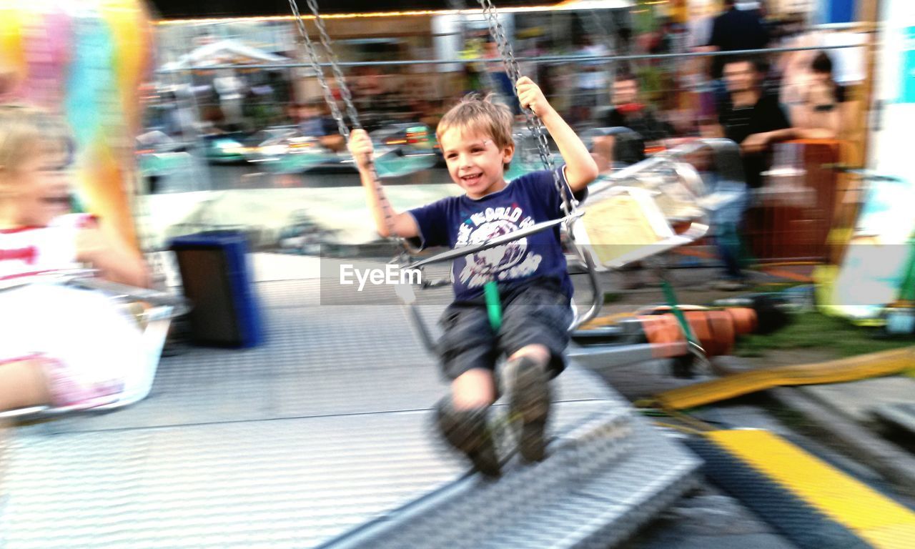 Happy boy enjoying in chain swing ride at amusement park
