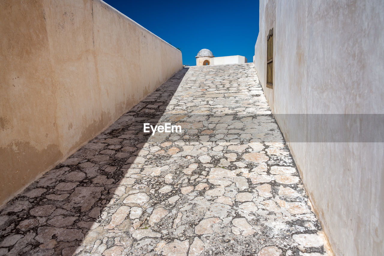 Empty footpath leading towards fort san miguel during sunny day