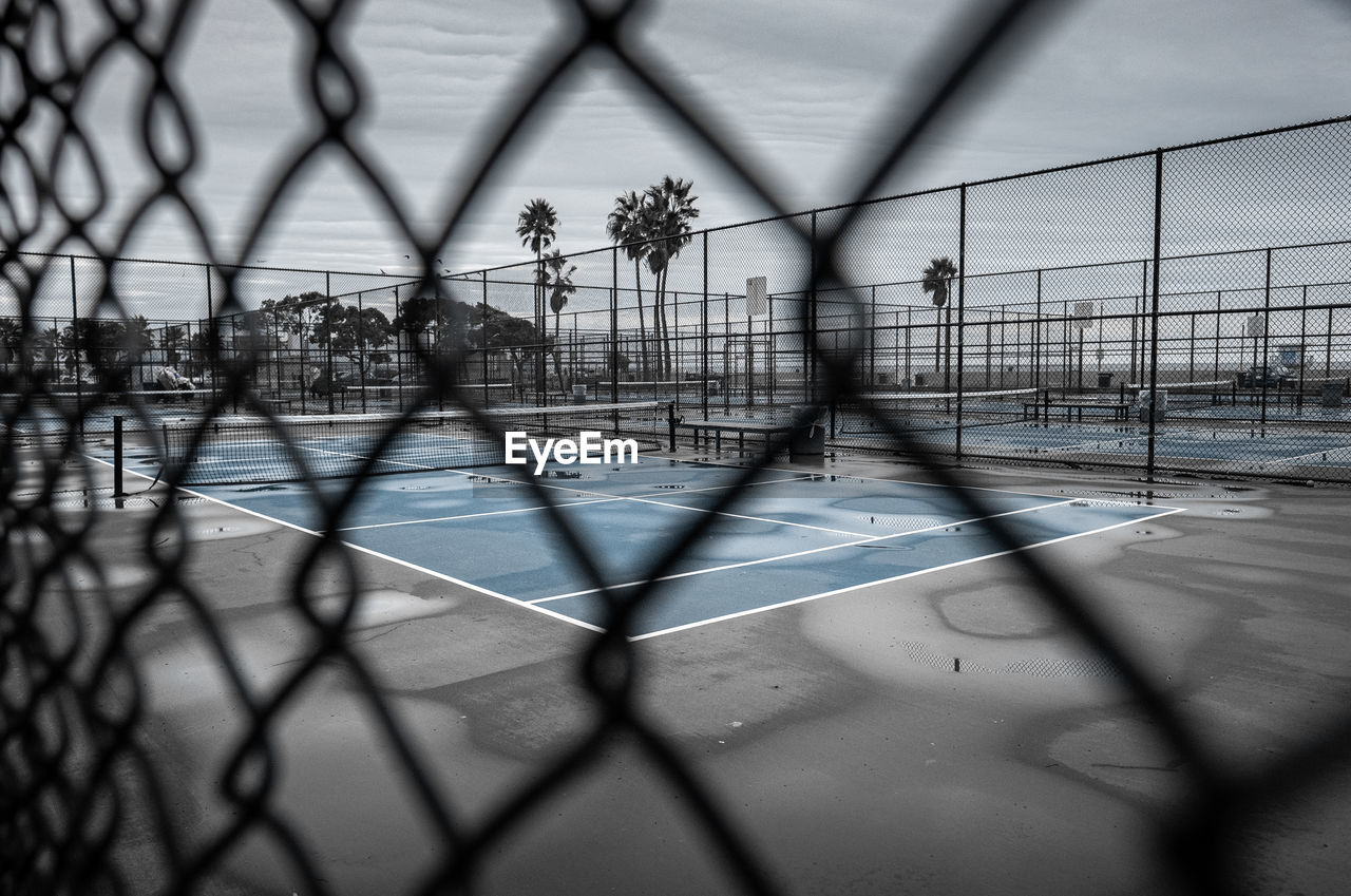 SHADOW OF CHAINLINK FENCE AND TREES IN CITY