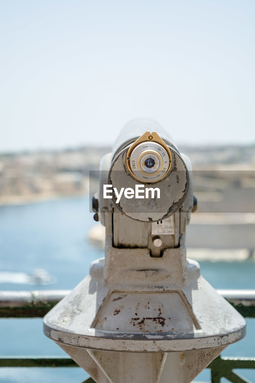 Close-up of coin-operated binoculars by sea against sky