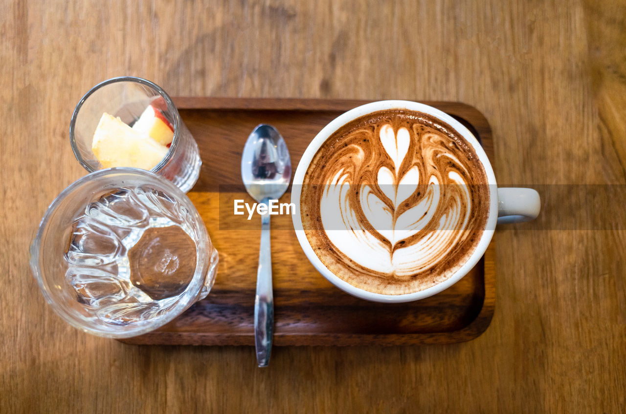 A cup of latte on wooden table .