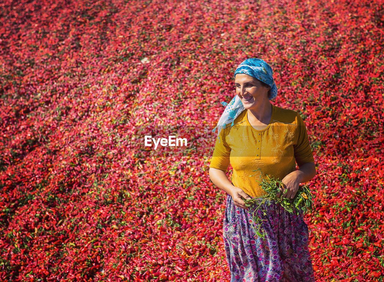 Smiling woman standing against red chili peppers