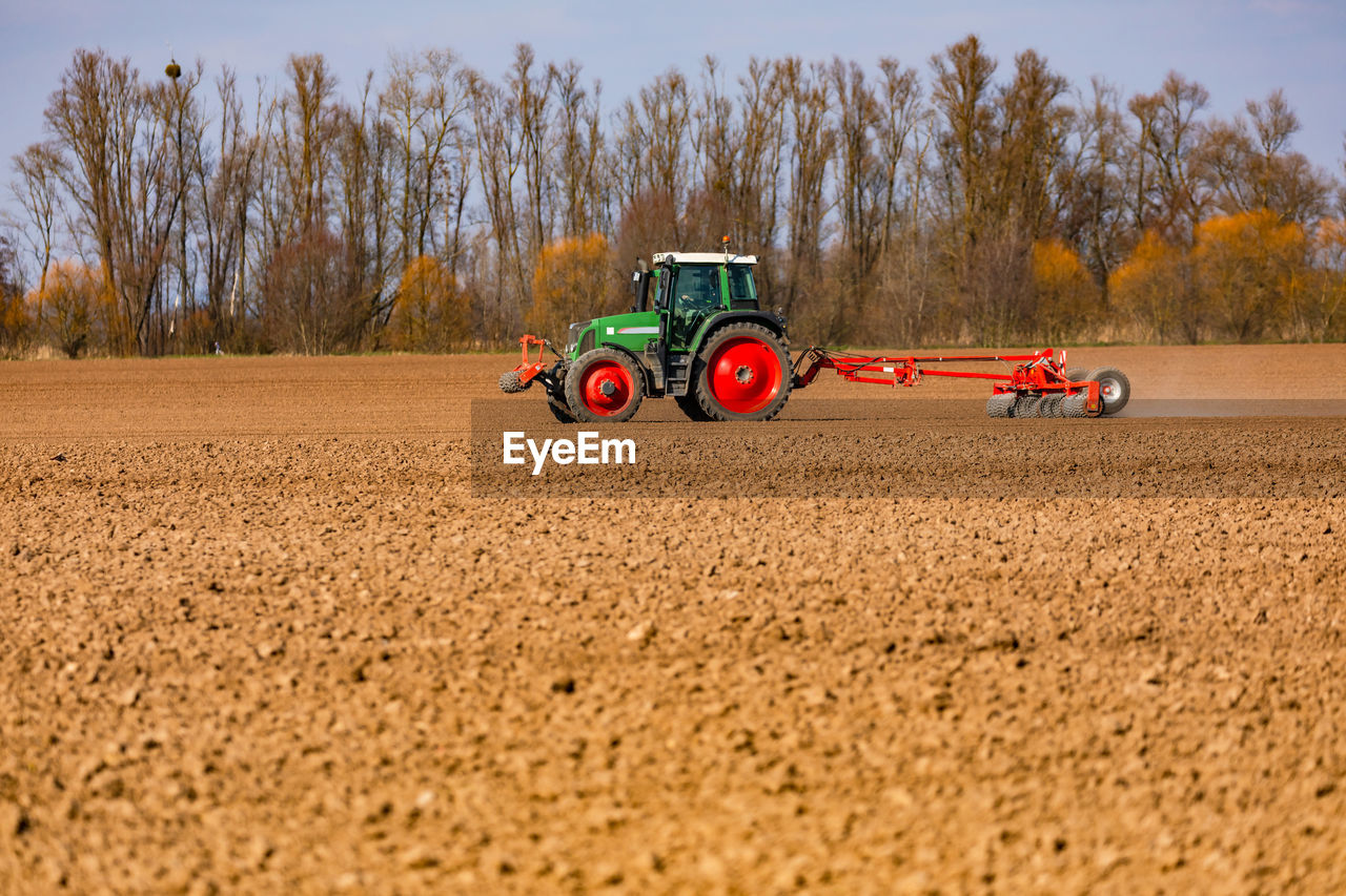 Rural idyll with a tractor plowing a field with a plow in the sun in spring