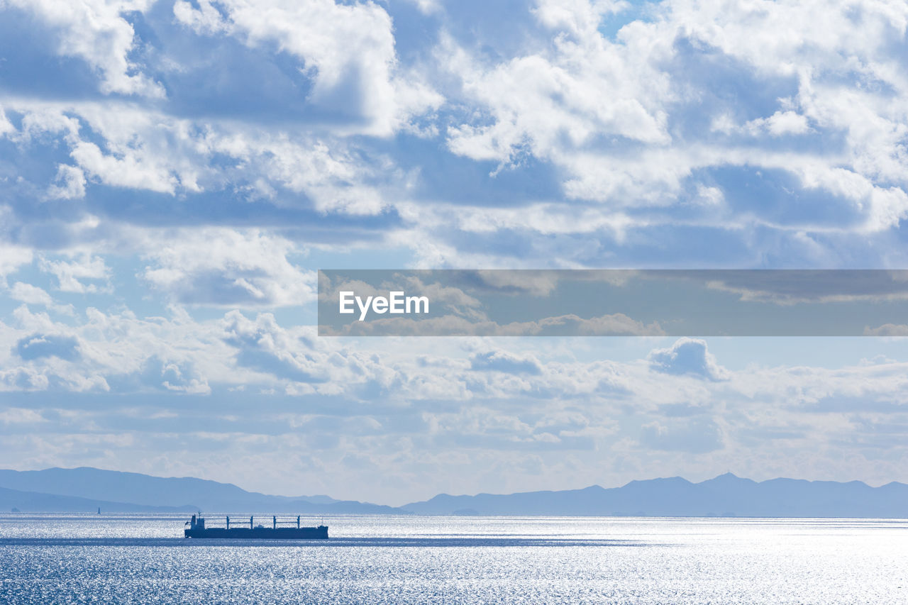 Boats in sea against cloudy sky