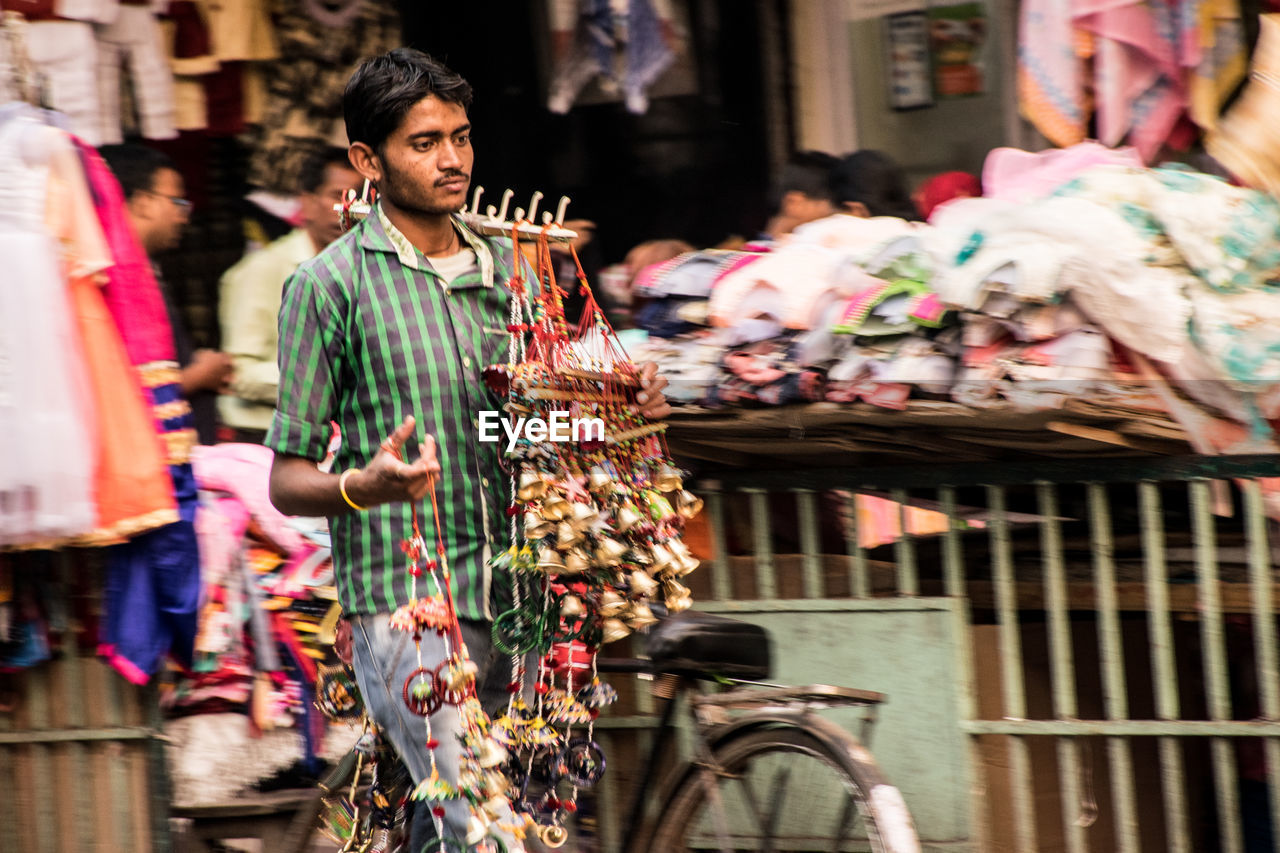 Man looking away while selling decorations on street in city