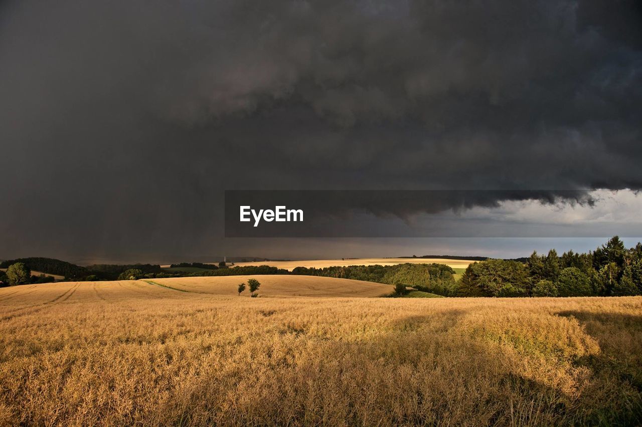 Scenic view of field against storm clouds