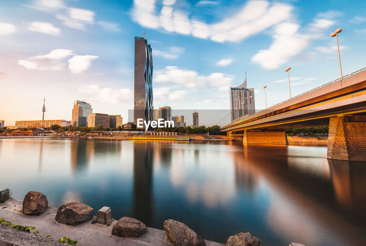 BRIDGE OVER RIVER AND BUILDINGS AGAINST SKY