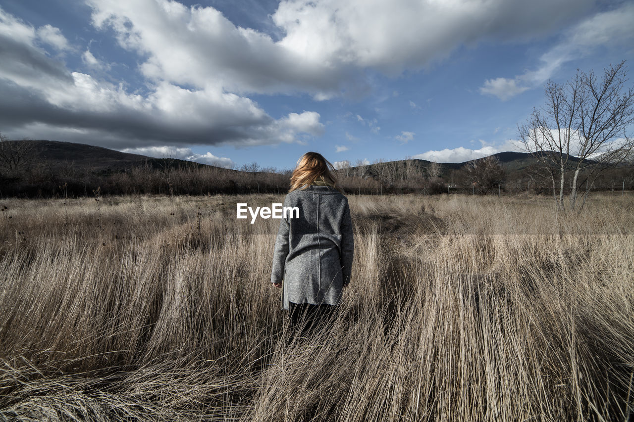 Rear view of woman standing on field against sky