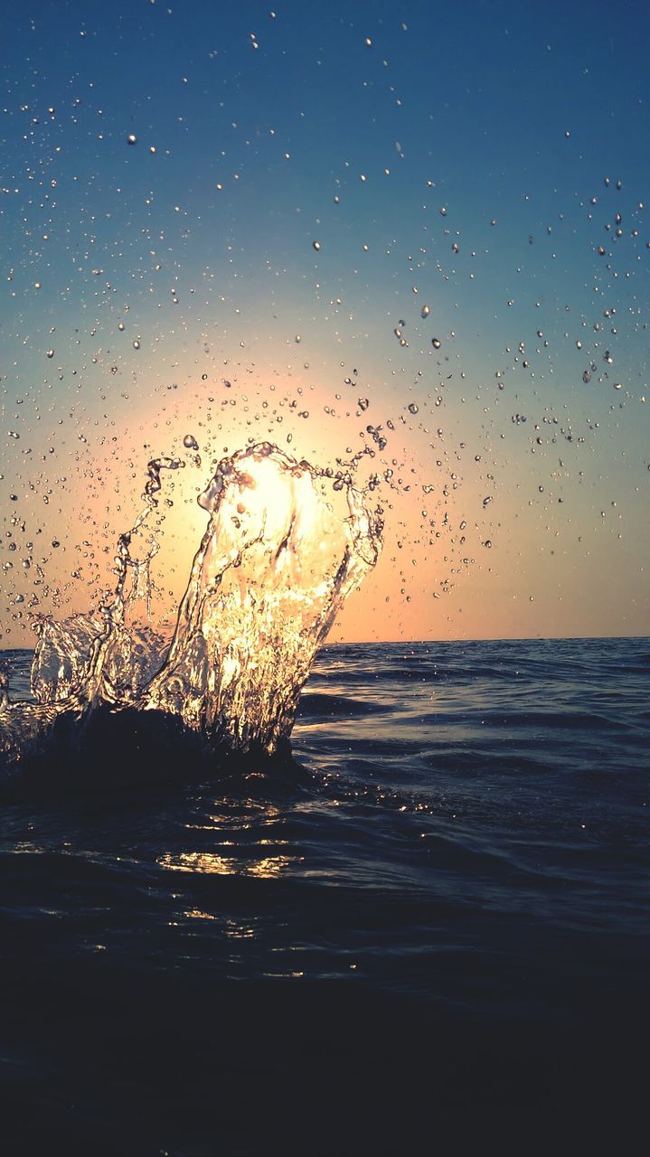 Close-up of water splashing in sea at sunset