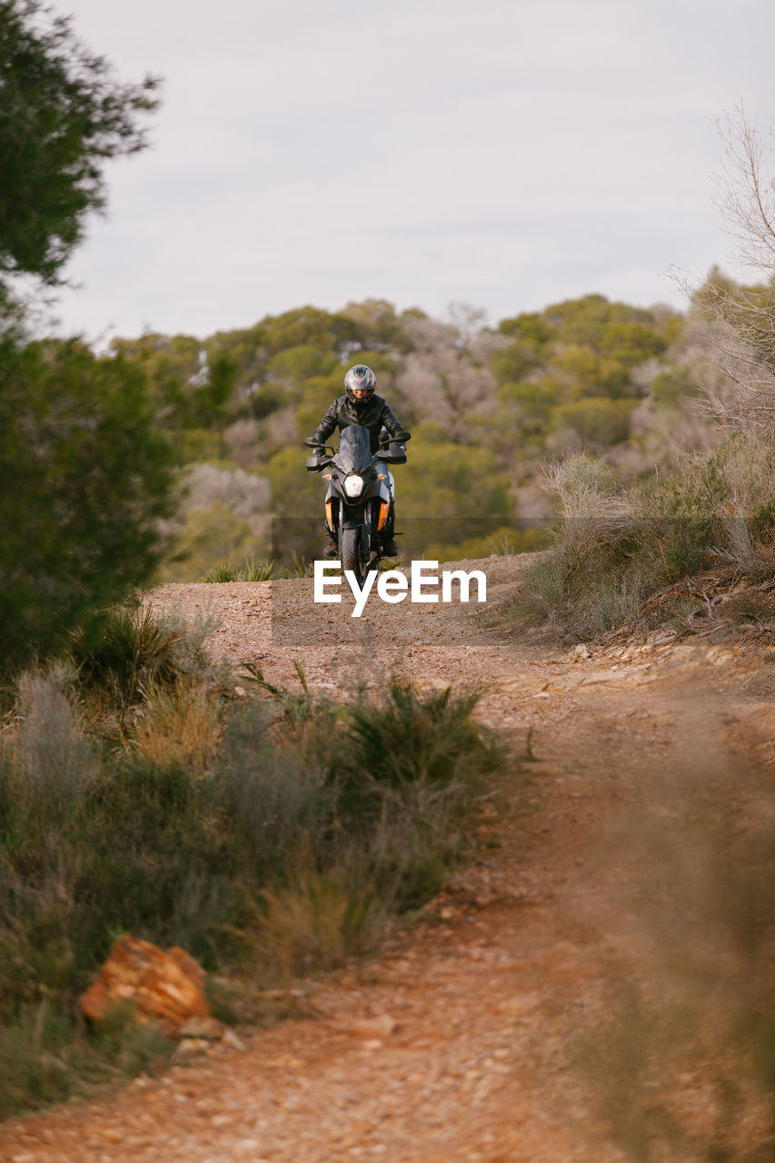 REAR VIEW OF MAN CYCLING ON GRASS