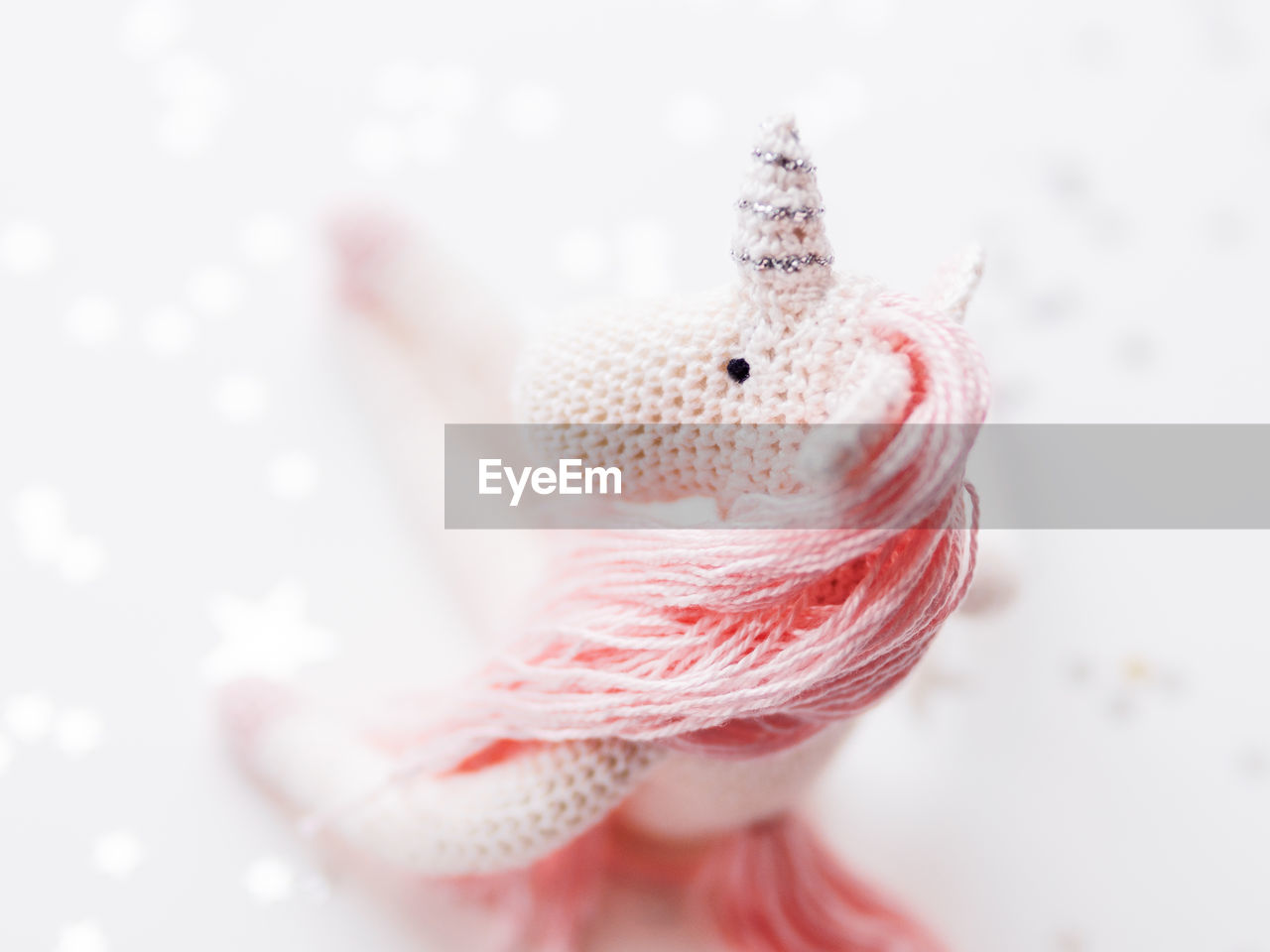 Cute fairy unicorn with pink mane. crocheted hand made toy on white background with silver stars.